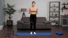 Fit woman fitness trainer blogger in sportswear teaches tells student doing leg exercise with loop band. Muscular sports girl record online remote webinar master class course lesson, workout at home