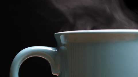 Close up hot coffee cup with nature steam smoke of coffee on wooden table, black background with copy space. Coffee and Tea Drink Concept.
