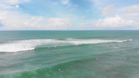 A group of young people learn to surf off the Indonesian coast of Bali in Canggu. Surfing, drone, aerial view, summer, vacation, holidays, sea, ocean. 4K Video Footage