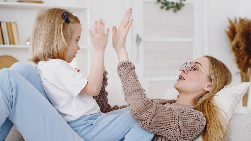 Top view on mom and cute daughter playing patty cake at home, carefree ...