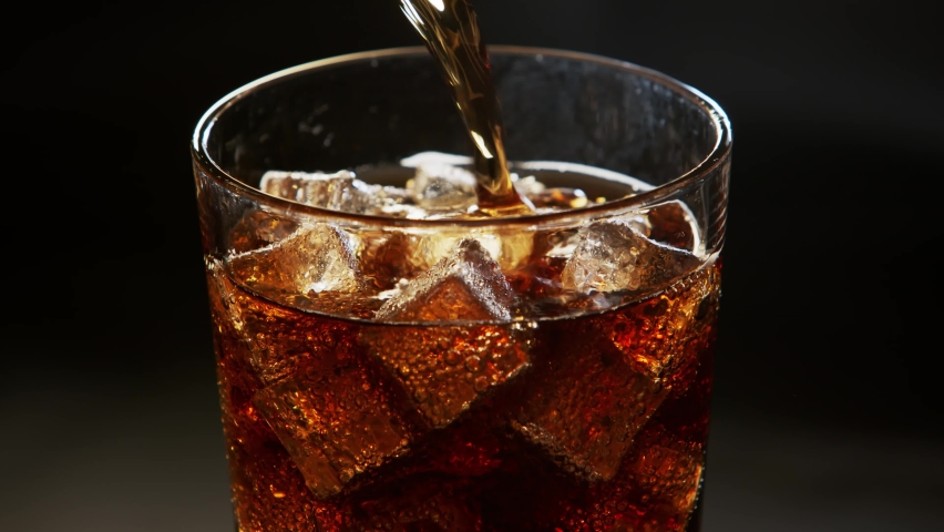 Pouring Cola with ice cubes. Cola with Ice and bubbles in glass. Soda closeup. Food background. Rotate glass of Cola. Slow motion 4K video footage. Macro Shot. Close-up. | Shutterstock HD Video #1071083542