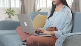 Asian Female Working On Laptop And Smiling At Living Room While Sitting On Sofa, Video In 4K
