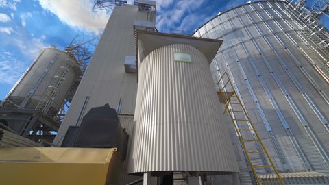 Exterior of aluminum equipment of a modern complex. Thick white smoke goes into the air from the large agricultural plant during grain processing.