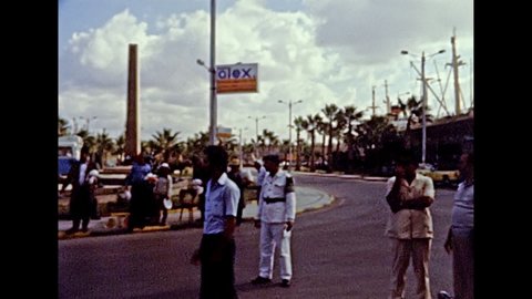 Alexandria, EGYPT, AFRICA - circa 1981: Egyptian police guiding tourists on tour to touristic buses on the street of the Alexandria. Vintage cars in traffic. Historical archival of Egypt in the 1980s.