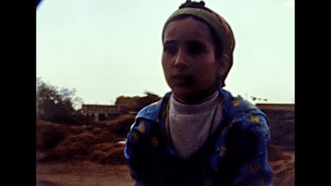 EGYPT, AFRICA - circa 1981: Egyptian girl asking for donations to a touristic bus on the road to Cairo city. Historical archival of Egypt in the 1980s.