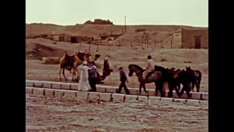 CAIRO, GIZA, EGYPT, AFRICA - circa 1981: Egyptian Bedouin men riding horses in Giza archaeological site. Valley Temple of Khafre ruins in Cairo city. Historical archival of Giza of Egypt in the 1980s