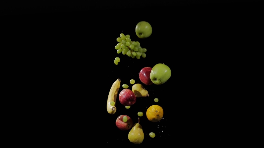 Wet fresh banana, apples, grapes, pear, lemons fly up and spinning with water splashes on a black background in slow motion shot, water drops on fruits - Powered by Shutterstock - Get 15% off with code: PIKWIZARD15