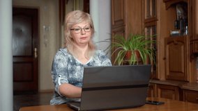 Senior woman 60s having a video call on her laptop. Online talk elderly people with family and friends remotely from home concept