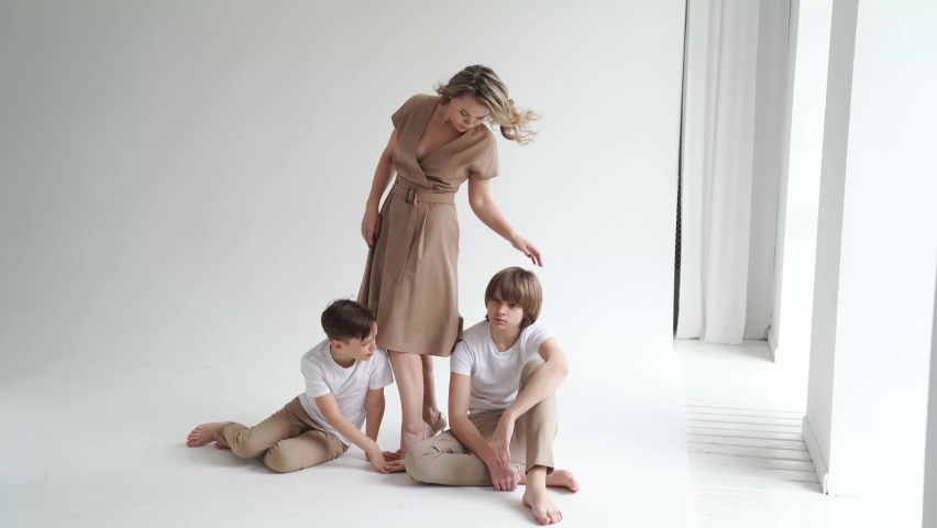 A mother and her two sons in beige and white clothes pose for a photo shoot in the studio. happy single mother. memorabilia for the family. Royalty-Free Stock Footage #1071093439