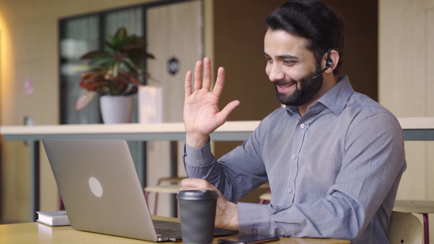 Happy indian business man customer support agent or salesman wearing headset talking, having virtual meeting working on laptop computer giving online training, remote class on video conference call. Royalty-Free Stock Footage #1071094678
