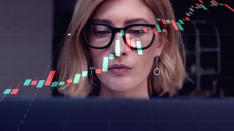 Portrait of attractive blond woman in glasses working on laptop to research financial markets. A businesswoman trader analyzing stock market rates to make the best investment solution. 4k, real time