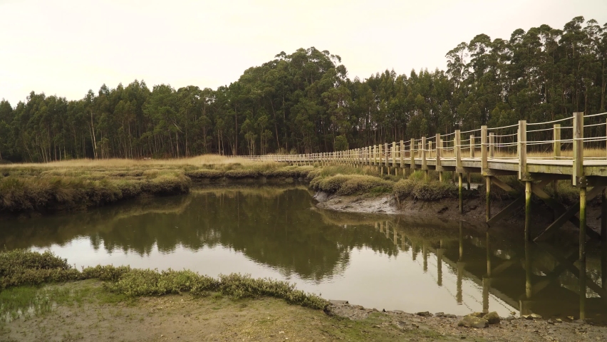 4K wooden food path over a low tide pond in the Ria de Aveiro on the estuary of the river Vouga. Royalty-Free Stock Footage #1071108520