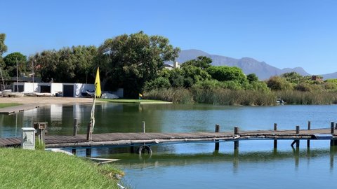Jetty wooden and slipway with grassy patch waters edge Zeekoevlei , pond or lake with mountain views