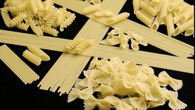  Several Types Of Pasta Rotating. This stock video shows a close-up shot of several types of pasta rotating on a black background.
