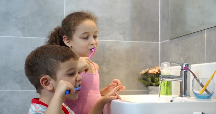 Portrait happy cute young children brushing teeth in bathroom and smiling. Children daily healthcare routine. Caucasian kids brushing looking at mirror at home. Lifestyle. | Shutterstock HD Video #1071122737