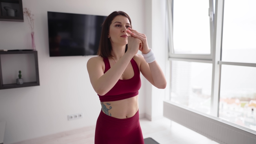 Athletic woman doing squats in her living room, wearing sportswear