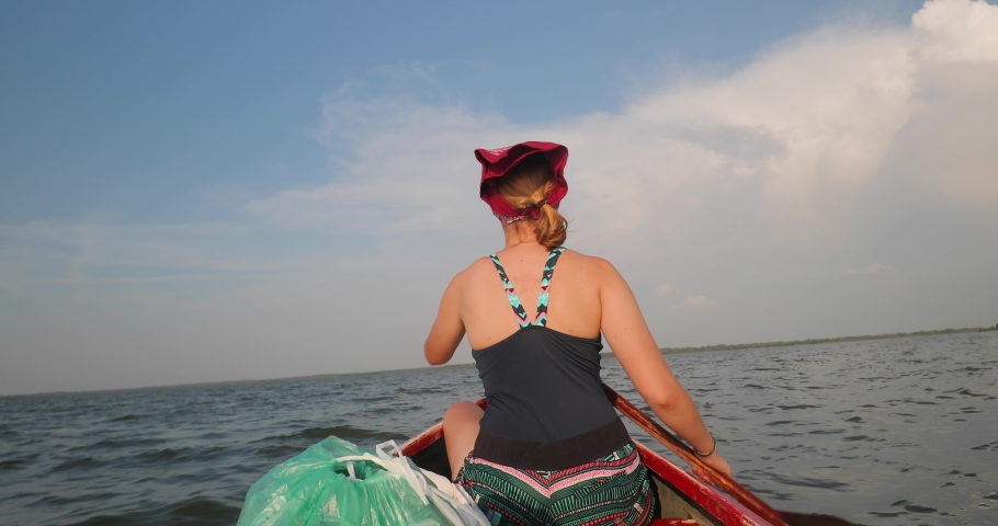 Canoeing in waves on an open lake surface, Lake Tisza, Hungary, girl paddling in front, slow motion from 60 fps footage