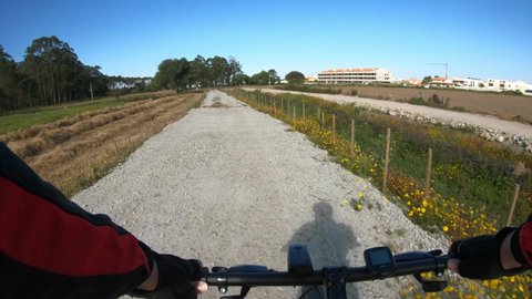 Esposende, Portugal, April 18, 2021: POV SHOT of biker riding bike. First Person View of a man cycling in the Esposende Interceptor Canal. Canalized stream flowing through the agricultural area.