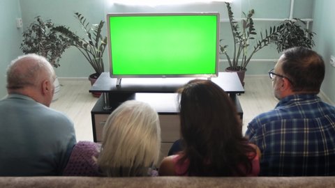 Family watching TV. Green screen.
A family of two generations is sitting on the couch at home. In front of them is a green screen TV. 