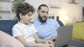 Dad and son making video call on laptop, smiling and talking, modern technology