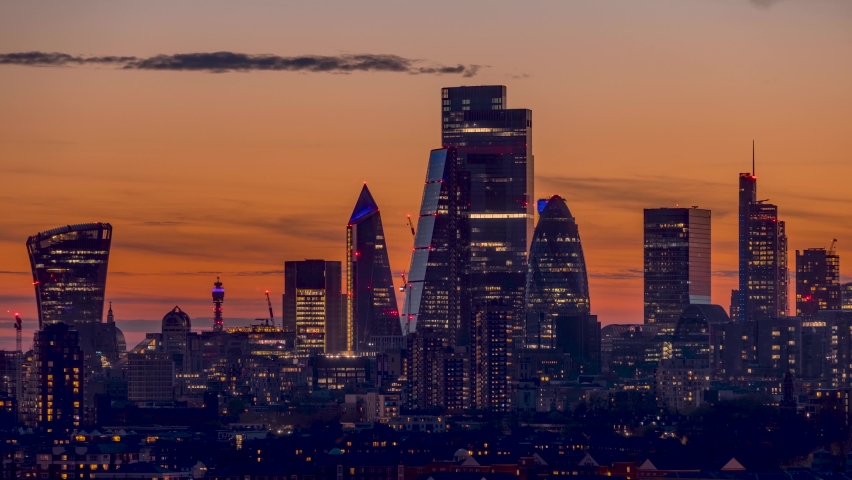 Sunset to night time lapse view of the skyline of the City of London with the sun dropping behind the different shaped offices skyscrapers, United Knigdom