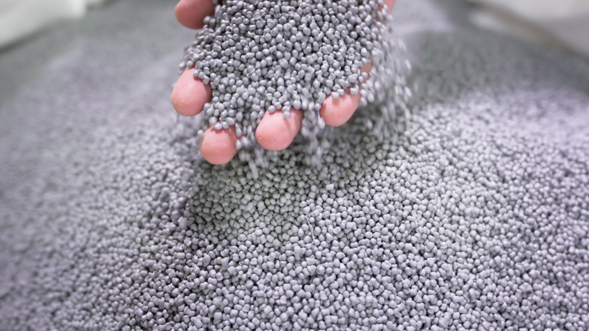 Hands lift white polymer granules from a cloth bag in a garbage recycling plant. Plastic pellets are crumbling or poured from the palms. Raw materials for recycled plastic are used in manufacturing. | Shutterstock HD Video #1071140110