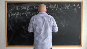 The teacher at the blackboard is a man of 40s without a face, writing down mathematical formulas with chalk. Online math lesson. - Powered by Shutterstock - Get 15% off with code: PIKWIZARD15