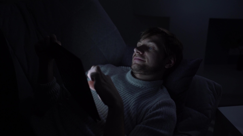 A man lying in bed uses a smartphone
