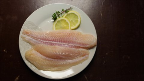 Panga fillets, Pterogymnus laniarius white fish from Asia, mild flavor with lemon slices and dark background