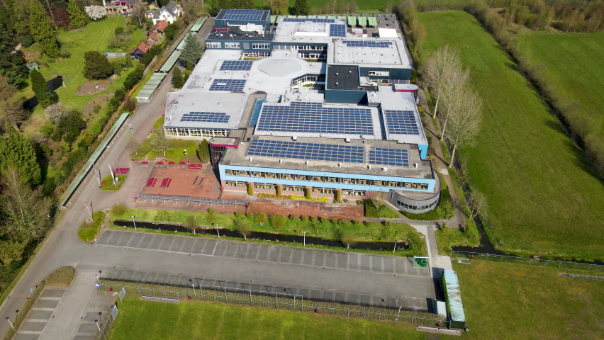 Flying over large high school with solar panels on rooftop