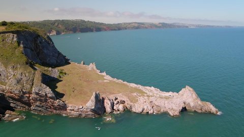 Beautiful landscape with rock formation with Long Quarry Point in Torquay and wide coastline in background. Devon, England. Aerial tilt down shot.