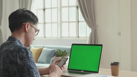 Asian Man Use Smart Phone And Laptop Computer With Green Screen Display At Home, Video In 4K
