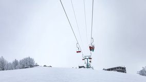 Ski lift, skiers and snowboarders. Winter in Carpatian mountains, ski resort landscape, UHD 8K timelapse video