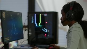 Furious african woman gamer with headset losing space shooter video game with graphics during gaming championship playing from home at RGB powerful personal computer, performing at esports tournament