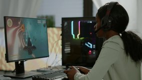 Pro african gamer playing online space shooter game on powerful computer using wireless controller and headset. Competitive cyber player woman performing videogame tournament use professional joystick