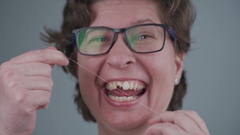 Adult woman with broken tooth uses dental floss. Importance of dental hygiene. Topic of care for cleanliness of oral cavity. Healthy and bad teeth. Dental care. Damaged tooth. Dental treatment