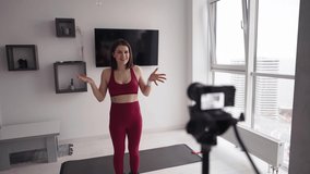 A young woman fitness instructor records a tutorial on home workouts on camera