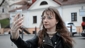 Happy Caucasian young woman talking with friends by video call via smartphone