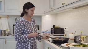 Woman cooking meals for dinner in modern white clean kitchen frying cutlets on electric stove. High quality 4k footage