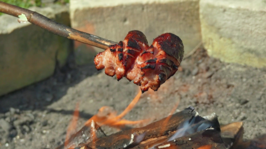 sausage baked on a stick. barbecue over the fire, preparing food outside.