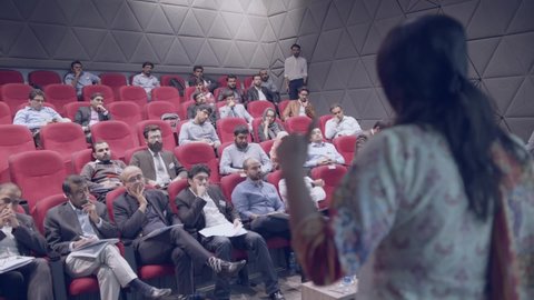 Unique over-the-shoulder shot shows female entrepreneur candidate presenting in front of expert jury members. Karachi, Pakistan. 15th Dec 2018