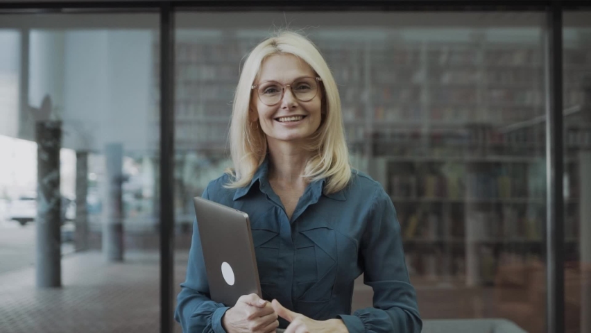 business woman with showing thumbs up, with laptop in hands in office
