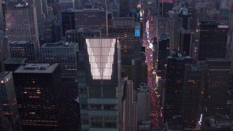 Stunning Futuristic Skyscraper Tower at Night in New York City with distant traffic and city lights flashing, Aerial revealing 7th Avenue Rush Hour Traffic in Manhattan above Skyline at Dusk