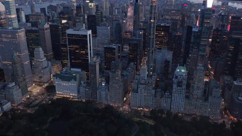Epic Aerial View of Tall New Manhattan Skyscraper Building with Glowing Bright Top at Sunset with traffic lights in the distance of New York City, Drone Shot