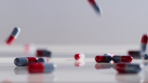 Close up shot of red and blue pills falling and bouncing on a surface