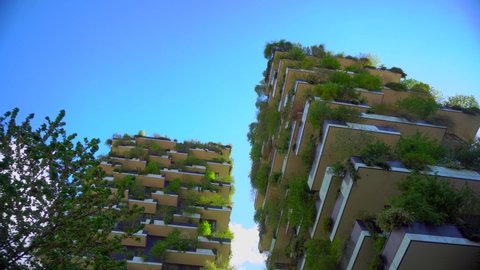 modern and eco-friendly skyscrapers with many trees on each balcony. Bosco Verticale. Modern architecture, vertical gardens, terraces with plants. Green Planet. Blue sky. Milan, Italy, April 2021: 