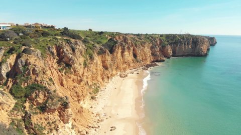 Canavial Beach framed by scenic cliffs in Lagos, Algarve, Portugal - Aerial Fly-over Tracking shot
