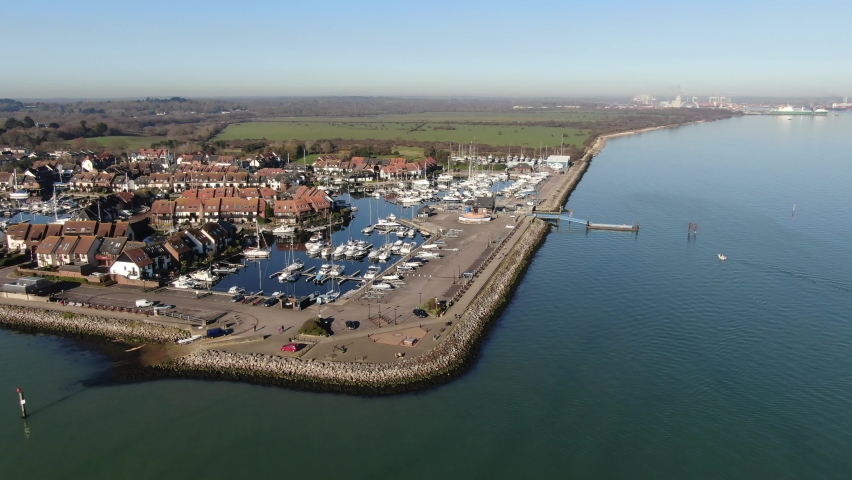 Boat marina on the South Coast of the UK. Sun and blue skies over the sailing boats, motorboats, pontoons and harbour. Luxury and expensive boat moorings. Aerial drone orbit shot of hythe marina lock