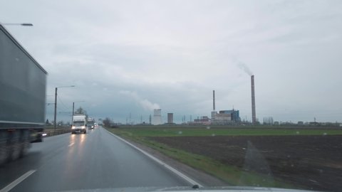 Car driving by disaffected coal-fired power plant in the field cloudy rainy day inside POV 4k no people