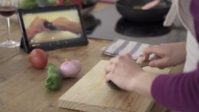 Cooking healthy food and following a recipe video tutorial on digital tablet. Hands cutting vegetables on cutting board while watching cooking show on screen - Powered by Shutterstock - Get 15% off with code: PIKWIZARD15